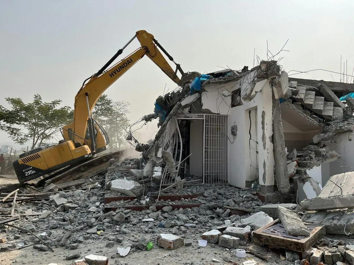 Excavator breaking down a damaged building